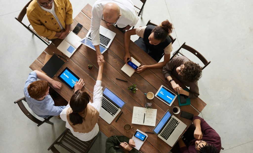 Top view of a diverse team collaborating in an office setting with laptops and tablets, promoting cooperation.